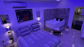 Un dormitorio moderno con una cama grande, un rincón de estar separado, una bañera y una pequeña mesa.