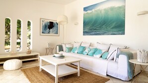 Een moderne woonkamer met een witte bank, een salontafel en een groot schilderij van een golf.