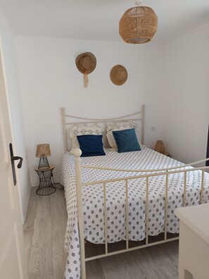 A bedroom with a bed, a bedside lamp, and a woven ceiling light fixture.