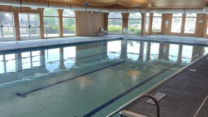 Ein Hallenbad mit deutlichen Fahrstreifenmarkierungen, einem Umkleidebereich und Blick ins Freie durch große Fenster.