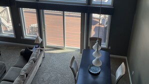 Ein Zimmer mit großem Fenster mit Blick auf eine Marina, einem Esstisch mit Stühlen, einer Couch und einem Deckenventilator.