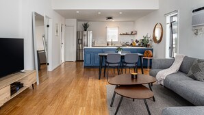A modern living room with a TV, sofa, and dining area. - Charming Lake Front Cottage (Swan Lake)