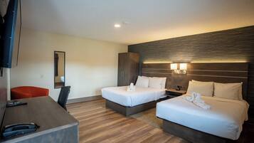 A hotel room with two beds, a desk, a chair, and a TV.