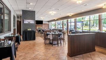A restaurant with a long counter, multiple tables, and a fireplace.
