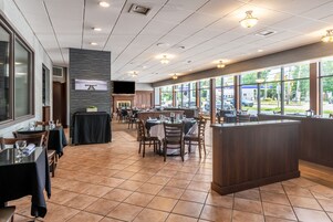 A restaurant with a long counter, multiple tables, and a fireplace.