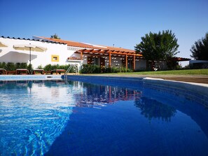 Una piscina al aire libre, sombrillas, sillones reclinables de piscina