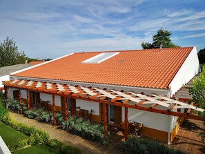 A house with a red-tiled roof, a wooden pergola, and a garden area. - Quinta de São Tomé (Évora)