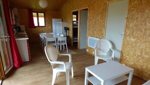 A compact room with a wooden floor, white furniture, a dining area with chairs and a table, and a door leading to another room. - Le Carbet Vendéen (Bouille-Courdault)