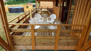 A wooden deck with a table and chairs, overlooking a pool and a small building. - Le Carbet Vendéen (Bouille-Courdault)