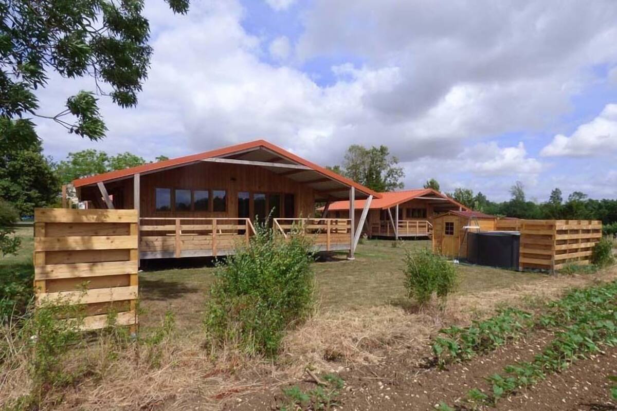 Un bâtiment en bois de style grange, doté d’un porche couvert et d’une zone délimitée par une clôture.