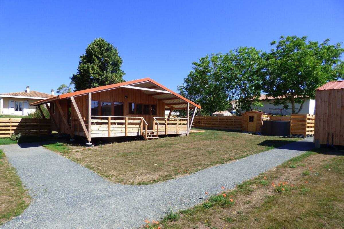 Une cabane en bois dotée d’un porche et d’un chemin de gravier menant à l’entrée.
