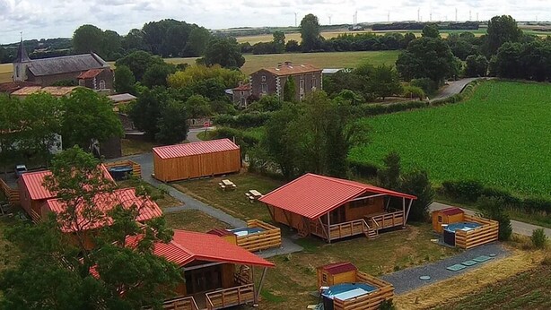 A rural area with several wooden cabins with red roofs, surrounded by fields and trees. - Le Carbet Vendéen (Bouille-Courdault)