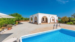 A pool area with a white building featuring arched doorways, a ladder, and potted plants. - Villa Cucunci by BarbarHouse (Ostuni)