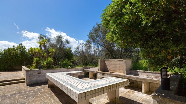 An outdoor patio area with a tiled table, stone flooring, and a brick structure. - 2947 Aia del Convento by BarbarHouse (Marittima)