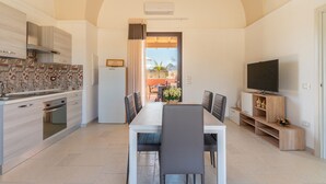 A modern kitchen with a dining area, a TV, and a view to the outside.
