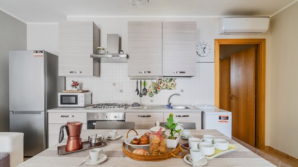 A modern kitchen with white cabinets, a stainless steel refrigerator, a microwave, and a coffee maker on the counter.