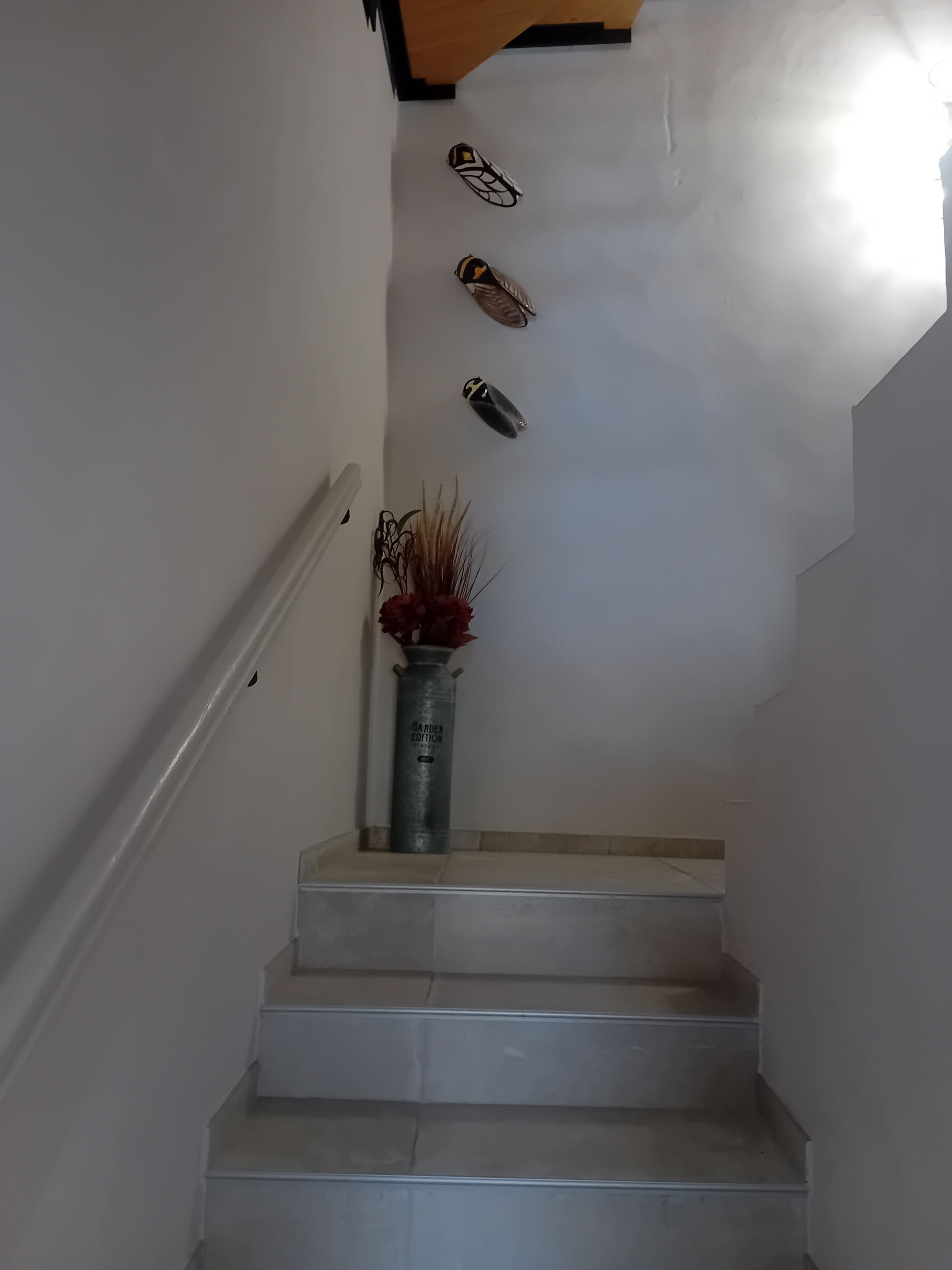 A staircase with a metal vase and a wall-mounted decorative item.