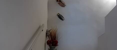 A staircase with a metal vase and a wall-mounted decorative item.