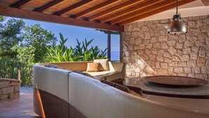 A cozy outdoor seating area with a stone wall and a view of the ocean. - Villa Ritter - VILLA RITTER MARIA (Marina di Campo)