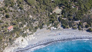 An aerial view of a coastal area with a beach, rocky terrain, and scattered buildings. - Villa Ritter - VILLA RITTER MARIA (Marina di Campo)