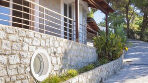 A stone-walled building with a circular window, a metal railing, and a covered porch. - Villa Ritter - VILLA RITTER MARIA (Marina di Campo)
