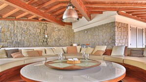 A spacious living area with a round wooden coffee table, a stone wall, and a wooden ceiling. - Villa Ritter - VILLA RITTER MARIA (Marina di Campo)