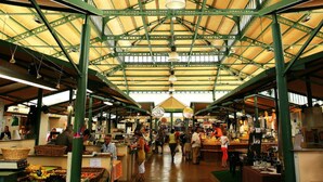 Un mercado interior con un techo metálico verde alto y vigas de madera.