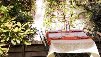 A table set outdoors with a white tablecloth, red napkins, and clear glassware.