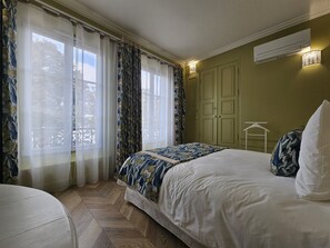 A bedroom with a bed, curtains, a wardrobe, and a hanging light fixture.