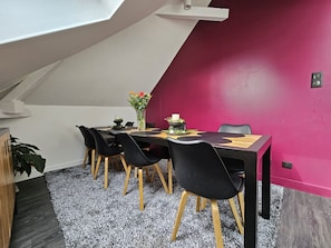 A dining area with a table, chairs, and a vase of flowers.
