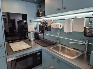 Una cocina moderna con lavavajillas incorporado, un lavamanos de acero inoxidable y una cafetera.