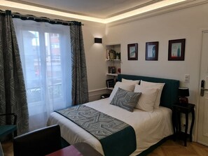 A neatly arranged bedroom with a bed, a bedside table, a chair, and a window with curtains.