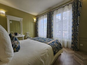 Un dormitorio con una cama grande, una mesita de noche, un espejo y una ventana con cortinas.