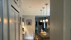 Une cuisine moderne dotée d’un îlot central, de luminaires suspendus et donnant sur l’espace repas.