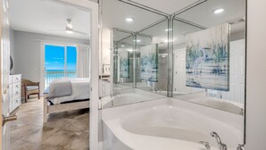 Un bagno moderno con una vasca da bagno ampia, un box doccia in vetro e uno specchio grande.