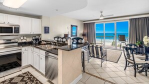 Una cocina moderna con una isla central, electrodomésticos de acero inoxidable y un comedor con vista al océano.