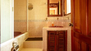 Une salle de bain avec une baignoire, un lavabo doté d’un distributeur de savon et une porte en bois.