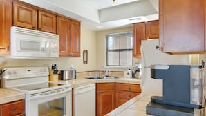 A kitchen with wooden cabinets, a microwave, stove, dishwasher, and a refrigerator.