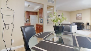 A modern dining area with a glass table, black chairs, and a vase of flowers.