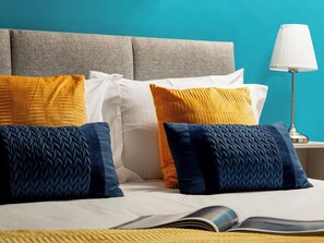 A neatly made bed with a variety of pillows and a book on it.