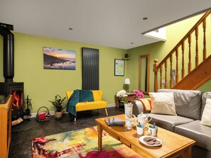 A cozy living room with a fireplace, a sofa, a coffee table, and a staircase.