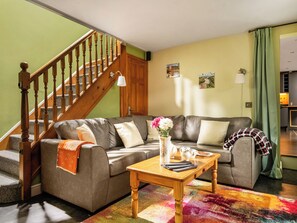 A living room with a grey sofa, wooden coffee table, and a staircase.