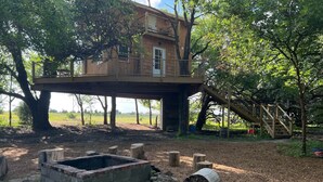 A treehouse with a wooden deck and a small staircase leading up to it. - Sunset Reset TreeHouse (Darlington)