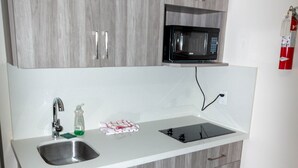 Una cucina con lavello in acciaio inossidabile, forno a microonde e pensili in legno.