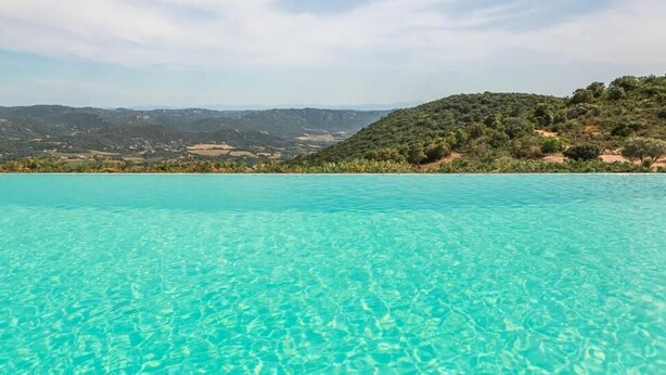 A clear blue pool with a view of a hilly landscape in the background. - Domaine de Piscia (Figari)