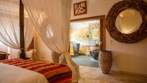 A bedroom with a bed, a canopy, a large mirror, and a view of the bathroom. - Domaine de Piscia (Figari)