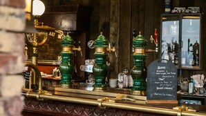 A bar counter with green beer taps, a chalkboard menu, and a wooden background. - Domaine de Piscia (Figari)