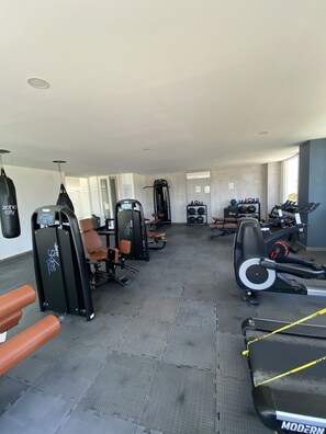Une salle de sport équipée de machines de cardio, de matériel de musculation et de tapis de sol pour les exercices.