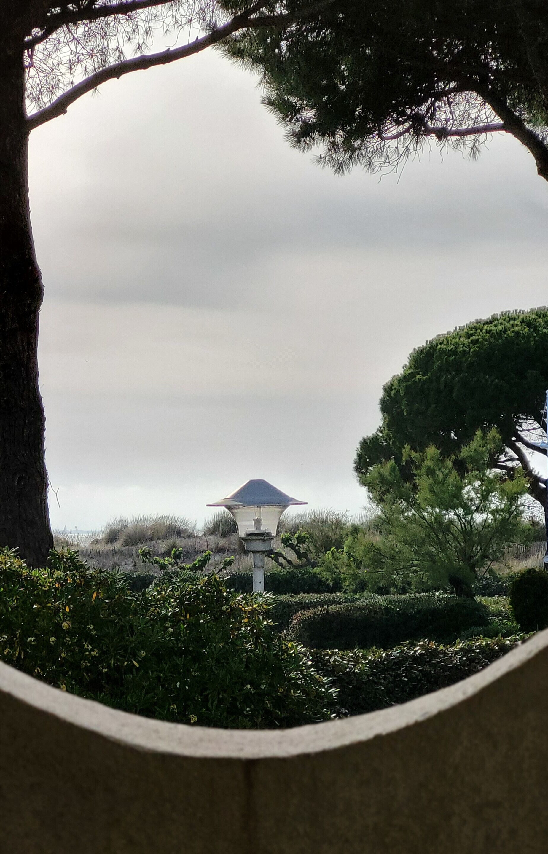 Une lanterne de style japonais traditionnel, placée sur une colline, d’où l’on peut admirer le ciel et la verdure environnante.