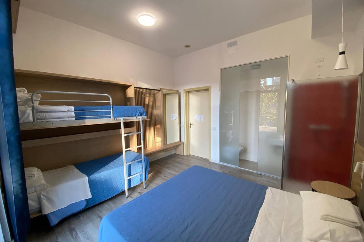 Een kamer met stapelbedden, een groot bed, een schuifdeur en een rode kast.
